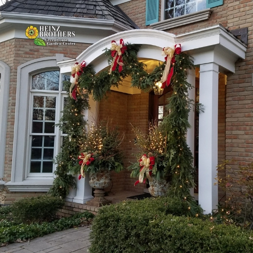 Front entrance of a home decorated with Christmas garland and ribbons