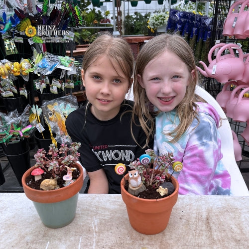 Two girls posing with atriums they made inside of the garden center at Heinz Brothers
