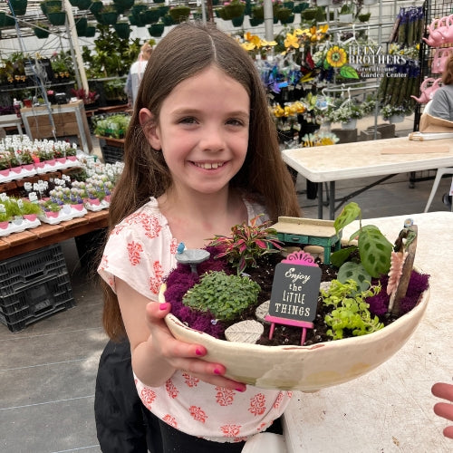 A girl posing with an atrium she made inside of the garden center at Heinz Brothers
