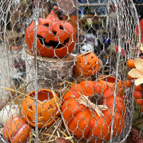 Decorative display of artificial and ceramic pumpkins with a chicken wire cage for table decoration