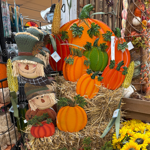 Decorative pumpkins and scarecrows on a hay bale with autumn-themed decorations.