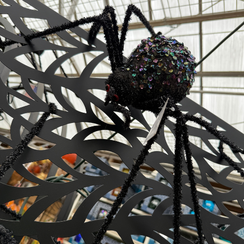 Large decorative spider with sequined body on a web indoors