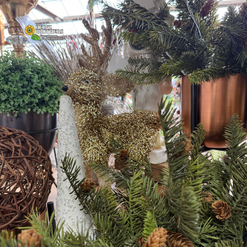 Decorative gold glitter deer among greenery and pinecones
