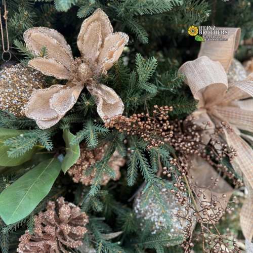 Decorative Christmas tree with gold flowers, ribbons, and ornaments.