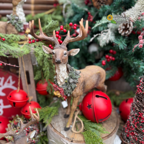 Decorative deer figure with red berries and jingle bells garland in a festive holiday setting.