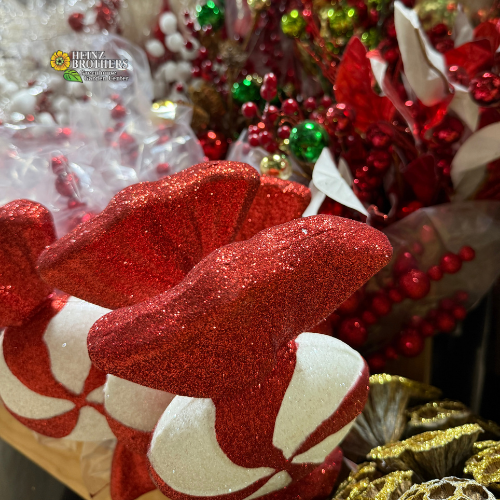 Decorative red and white glitter candy design pick surrounded by festive green and gold decorations decorations.