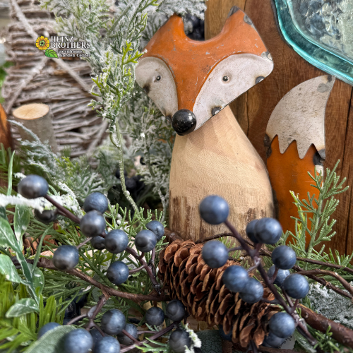 Metal fox ornament with blue berries and greenery on a rustic background